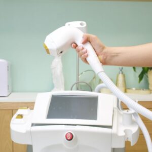 Close-up of a hand holding a laser hair removal device in a clinic setting.